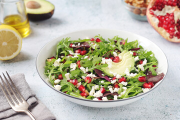 A plate with green rocket salad with pomegranate and avocado	