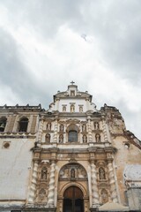 Fototapeta premium symmetrical view of ancient spanish colonial church ruins restored with proper sculptures of saints and cross on top