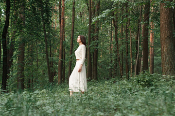 Fashionable beautiful young girl with a knitted sweater and skirt in the forest near the trees