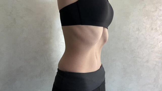 Woman demonstrating breathing exercises for core strength, showing abdominal movements as she inhales and exhales. Effective routine for core strengthening