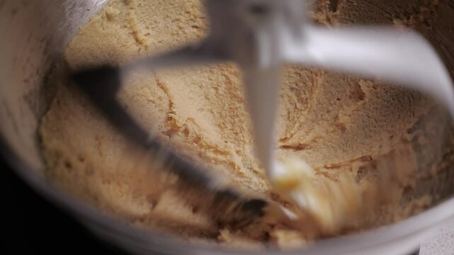 cooking in the kitchen. dessert making. cookie dough. close-up of butter and sugar in a steel mixer bowl. The ingredients are whipped with a paddle attachment at high speed. buttering