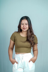 Portrait of a confident Asian woman smiling, standing looking at the camera isolated on a blue background