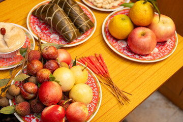 table with Zongzi and various fruits and a cake and peanuts as traditional offerings for the Dragon Boat Festival