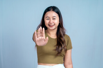 Young Asian woman wearing casual t-shirt over blue isolated background doing stop sign with palm of the hand.