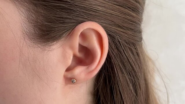 Close up of a moving ear with a stud earring. Ideal for medical, beauty, or jewelry projects. Shows subtle ear positioning shifts