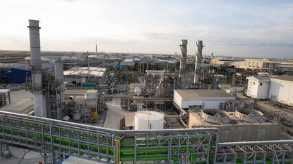 Oil refinery plant chemical factory and power plant with many storage tanks and pipelines at sunset. point of view from a Drone