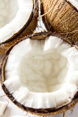 Close-up of halved coconuts showcasing fresh, white, juicy flesh and rough, textured brown shells.