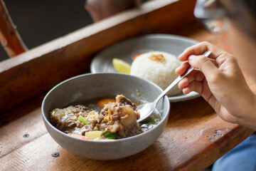 Sop Buntut or oxtail soup on a wooden table. traditional Indonesian culinary delights
