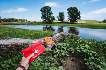A first-aid kit against the background of the river, first aid in nature, a red box with medicines,...