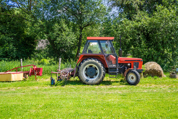 Naklejka premium Agricultural machinery in organic farming, red tractor with a plough on the back
