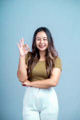 Fototapeta premium Young beautiful woman smiling joyfully and looking happy, feeling carefree and positive isolated by blue background