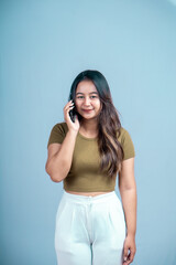 A young Asian woman with an expression holding a smartphone isolated on a blue background