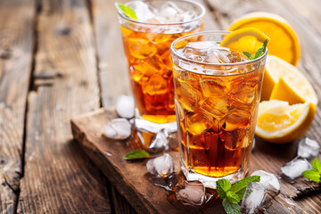 Ice tea with lemon. Cuba Libre or long island iced tea cocktail with strong drinks, cola, lime and ice in glass, cold longdrink or lemonade.