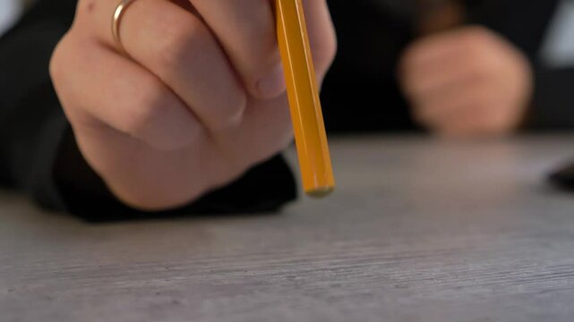 anxiety feeling. close-up of female hands with pencil. office worker quickly and nervously taps yellow pencil on table. stressful and difficult work in office. desicion maker