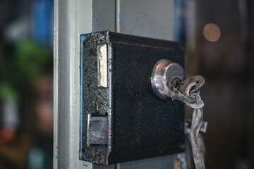 Close up shallow depth of field shot of old door lock with key inside. Both the door know and the key are rusty showing signs of heavy usage