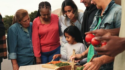 Happy multigenerational friends having fun preparing food at house rooftop - Diversity people lifestyle