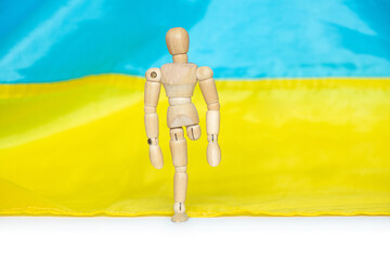 A wooden man without a leg against the background of the Ukrainian flag will lose his leg in the...