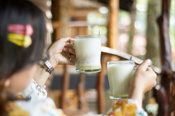 woman's hand holding warm pure cow's milk in a wooden cabin in the middle of the forest