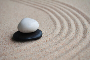 White and black zen stones on sand with customizable space for text