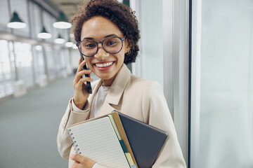 Stylish woman sales manager talking by phone with client standing on coworking background 