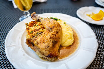 Baked chicken leg with pastry stuffing, mashed potato, white plate.