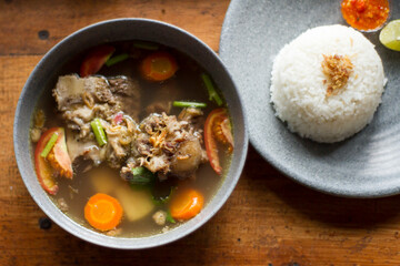 Sop Buntut or oxtail soup on a wooden table. traditional Indonesian culinary delights