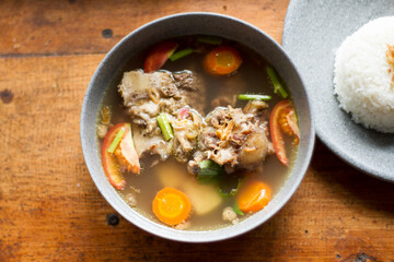 Sop Buntut or oxtail soup on a wooden table. traditional Indonesian culinary delights