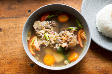 Sop Buntut or oxtail soup on a wooden table. traditional Indonesian culinary delights