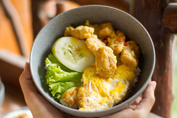hands carrying crispy salted egg dori, in a wooden-themed cafe