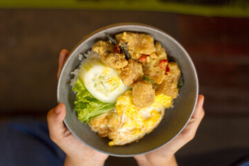 hands carrying crispy salted egg dori, in a wooden-themed cafe