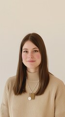 Obraz premium A young woman with long brown hair is wearing a tan sweater and a simple necklace