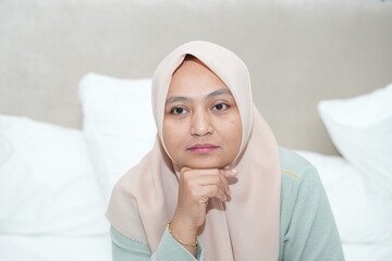 Portrait of an Asian woman wearing a hijab in the bedroom