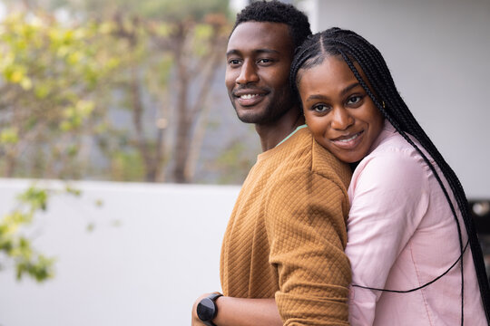 Young couple embracing and smiling, enjoying time together at home, copy space