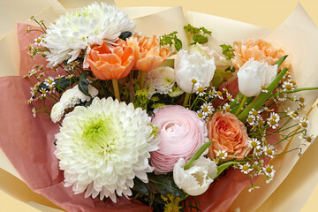 Beautiful bouquet of different flowers wrapped in yellow designer paper