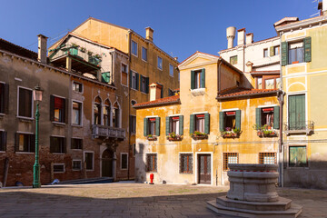 Small Venetian traditional square with old medieval houses and a well in Venice, Italy