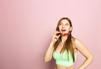 A woman is holding glasses and wearing a green top and shorts on a pink background. Beautiful...
