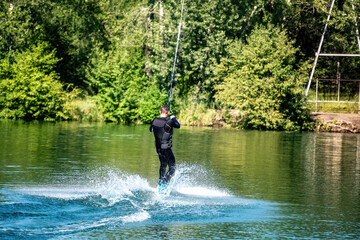 A young man uses a rope for wakeboarding.