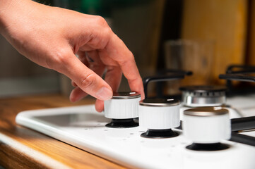 woman's hand turns on the gas stove. protection from children. Gas systems concept. Gas stove with electric ignition