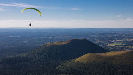 parapente survolant la chaîne des Puys, également appelée Monts Dôme, un groupe d'environ 80 volcans situé sur le plateau des Dômes au nord du Massif Central, en France.