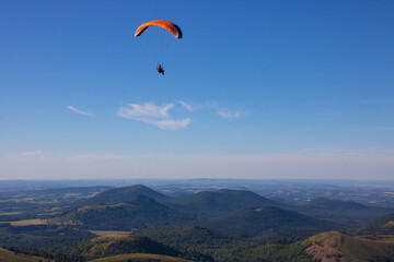 parapente survolant la chaîne des Puys, également appelée Monts Dôme, un groupe d'environ 80 volcans situé sur le plateau des Dômes au nord du Massif Central, en France.