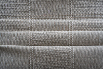 Folds of linen fabric with a fine, woven texture. The soft, neutral tones and subtle pattern create a serene and sophisticated visual, ideal for backgrounds, textile design, or home decor projects.