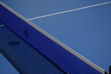 Mesa de ping pong azul con la sombra de pelota sobre la red.