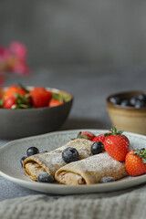 Crepes with ricotta cheese served on the plate with blueberries, strawberries and cherries