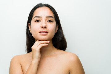 Studio portrait of a peaceful hispanic woman showing off her flawless skin, embodying natural beauty and skincare regimen