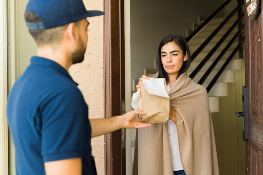 Courier delivering a package of medications to a woman wrapped in a blanket