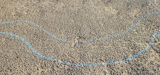Two blue curved wavy lines are drawn in chalk on the asphalt.