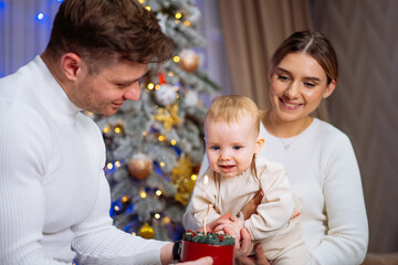 Obraz premium Family Celebrating Babys First Christmas. A family celebrates Christmas with a baby in front of a decorated tree.