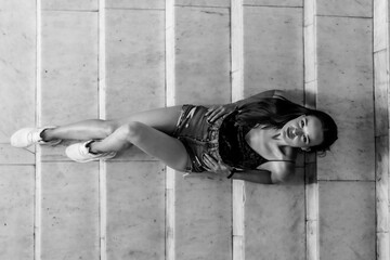 Woman Lying On Stone Steps. A black and white photo of a young woman lying on stone steps, looking...