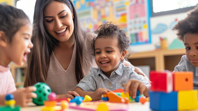 smiling teacher and happy preschool children playing together with colorful toys at kindergarten