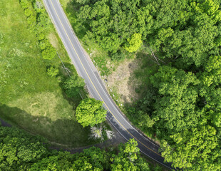 looking down at empty road from above (drone shot of highway) green trees landscape countryside driving scenic country usa north america
